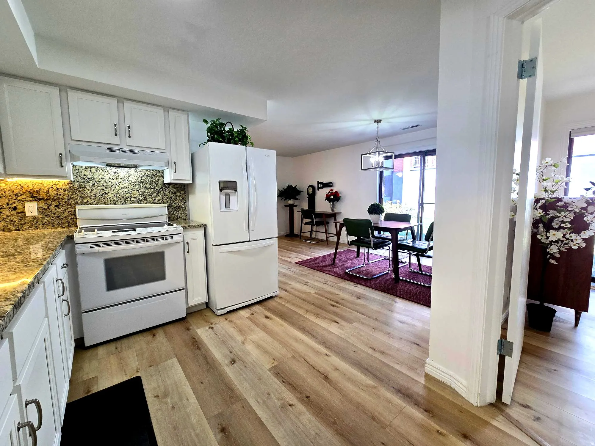Kitchen with white appliances, white cabinets, and granite backsplash & countertops.