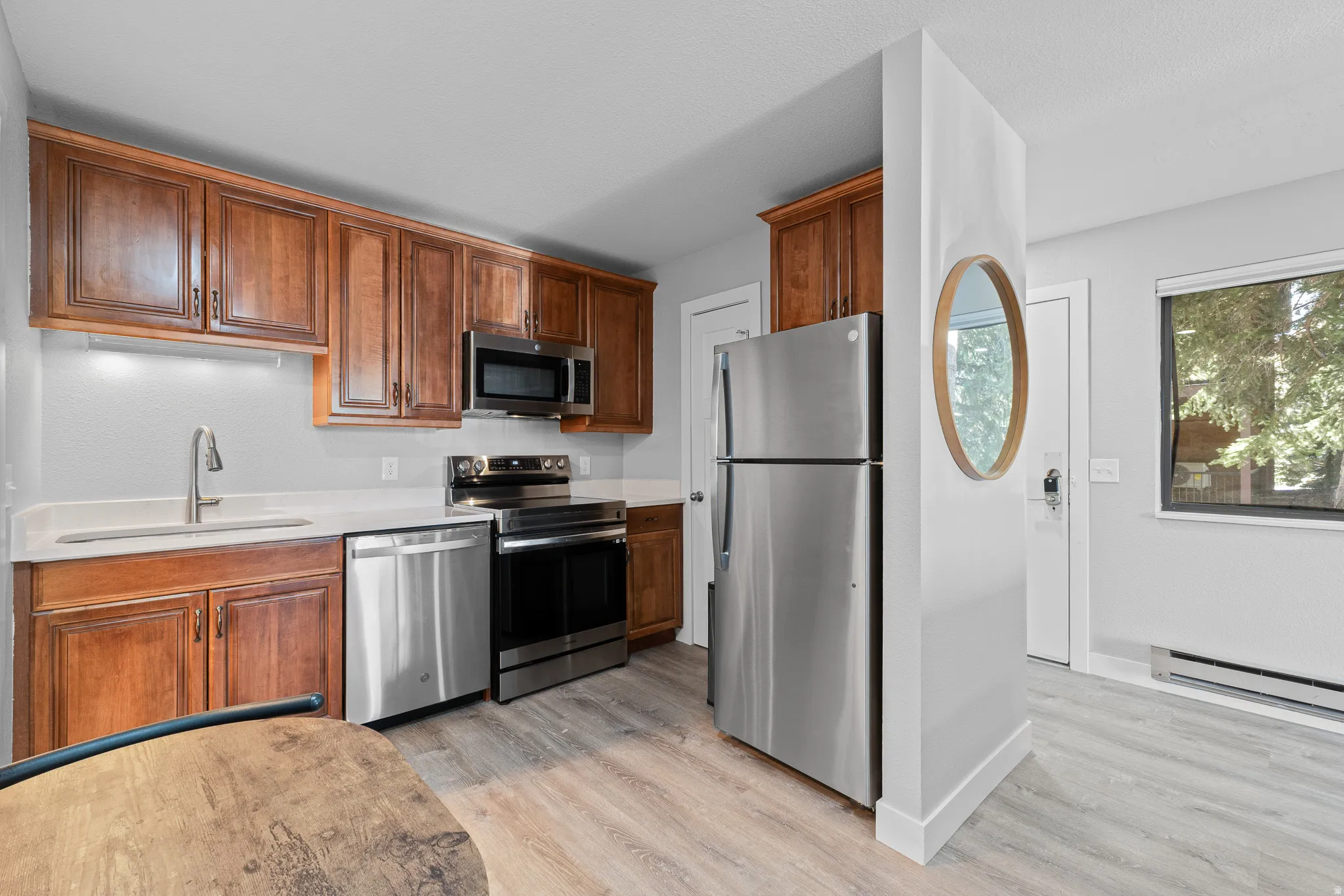 Kitchen featuring stainless steel appliances, light wood-type flooring, wood finish cabinets, and a baseboard radiator