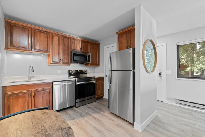 Kitchen featuring stainless steel appliances, light wood-type flooring, wood finish cabinets, and a baseboard radiator