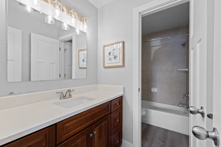 Bathroom with vanity, shower / washtub combination, dark wood-type flooring, and a textured wall