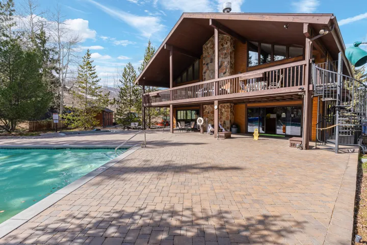 Rear view of property with stone siding, a community pool, and a patio area