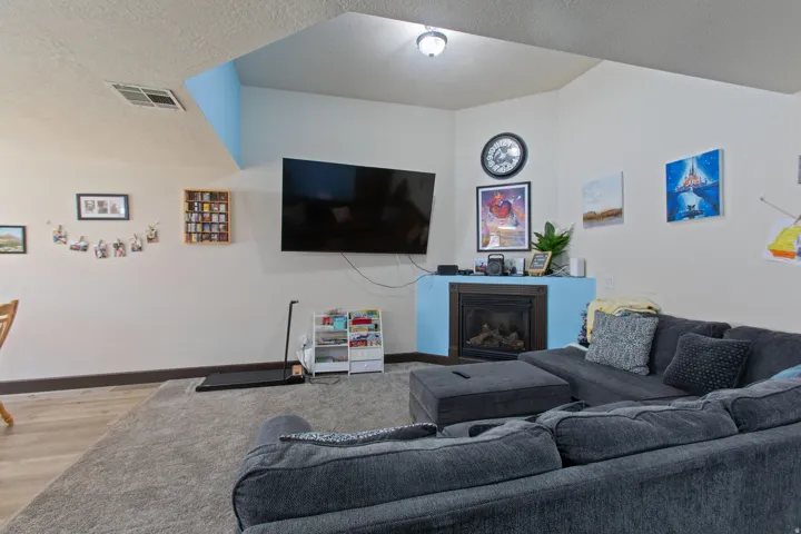 Living room with a glass covered fireplace, a textured ceiling, and wood finished floors