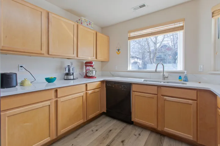 Kitchen with light wood finish cabinetry, black dishwasher, and light wood finished floors