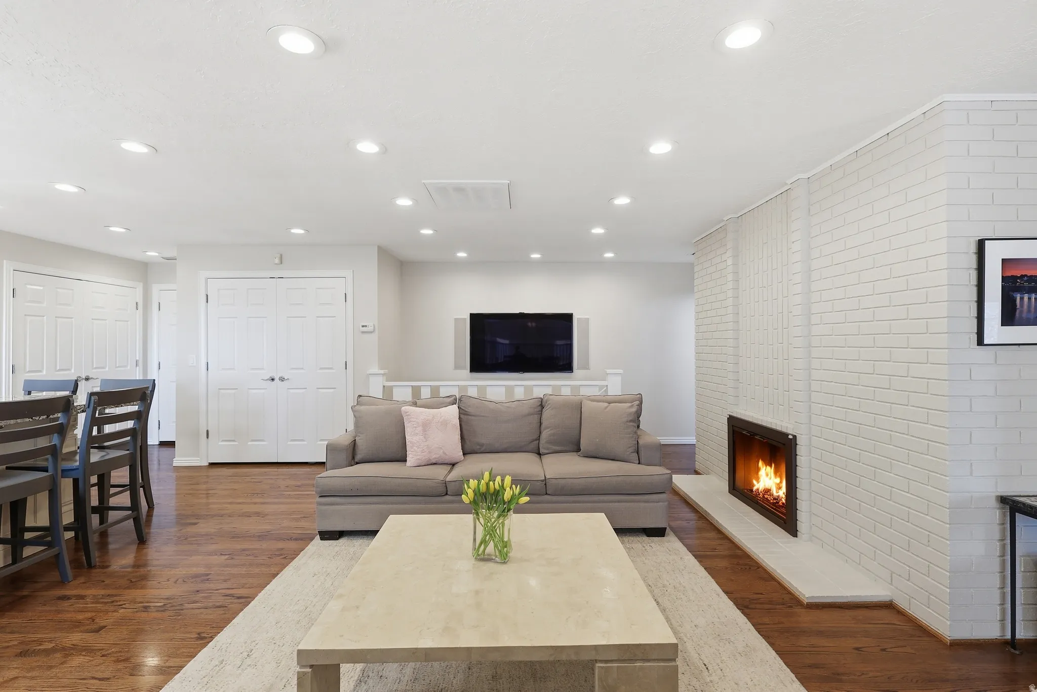 Living area featuring dark wood-type flooring, a brick fireplace, brick wall, and recessed lighting