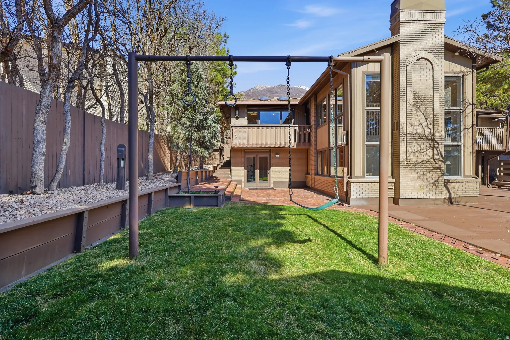 Rear view of house with brick siding, french doors, a patio, and a chimney