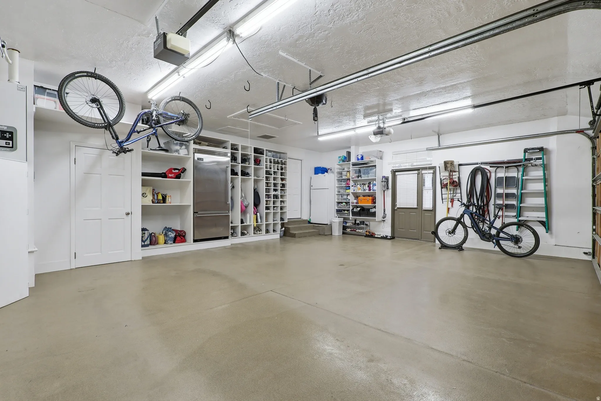 Garage featuring freestanding refrigerator and a garage door opener