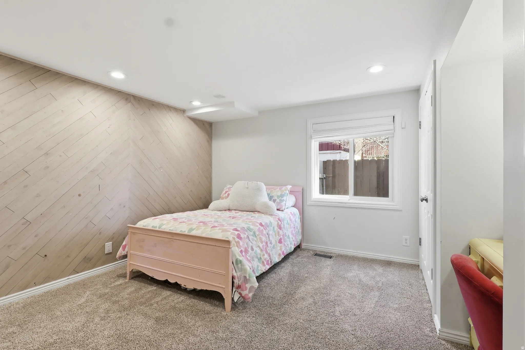 Carpeted bedroom with wood walls and recessed lighting