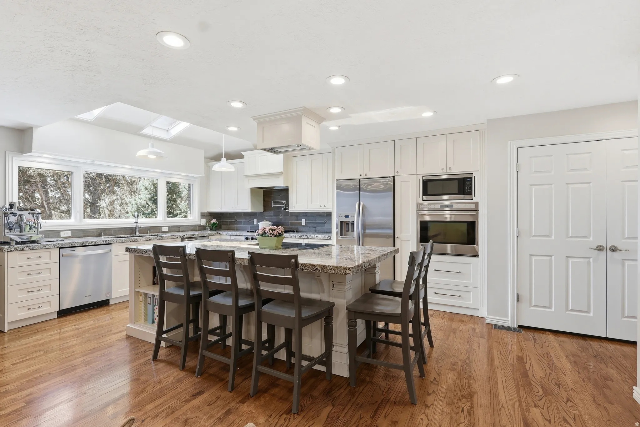 Kitchen featuring light stone counters, stainless steel appliances, a kitchen island, a breakfast bar area, and light wood-style floors