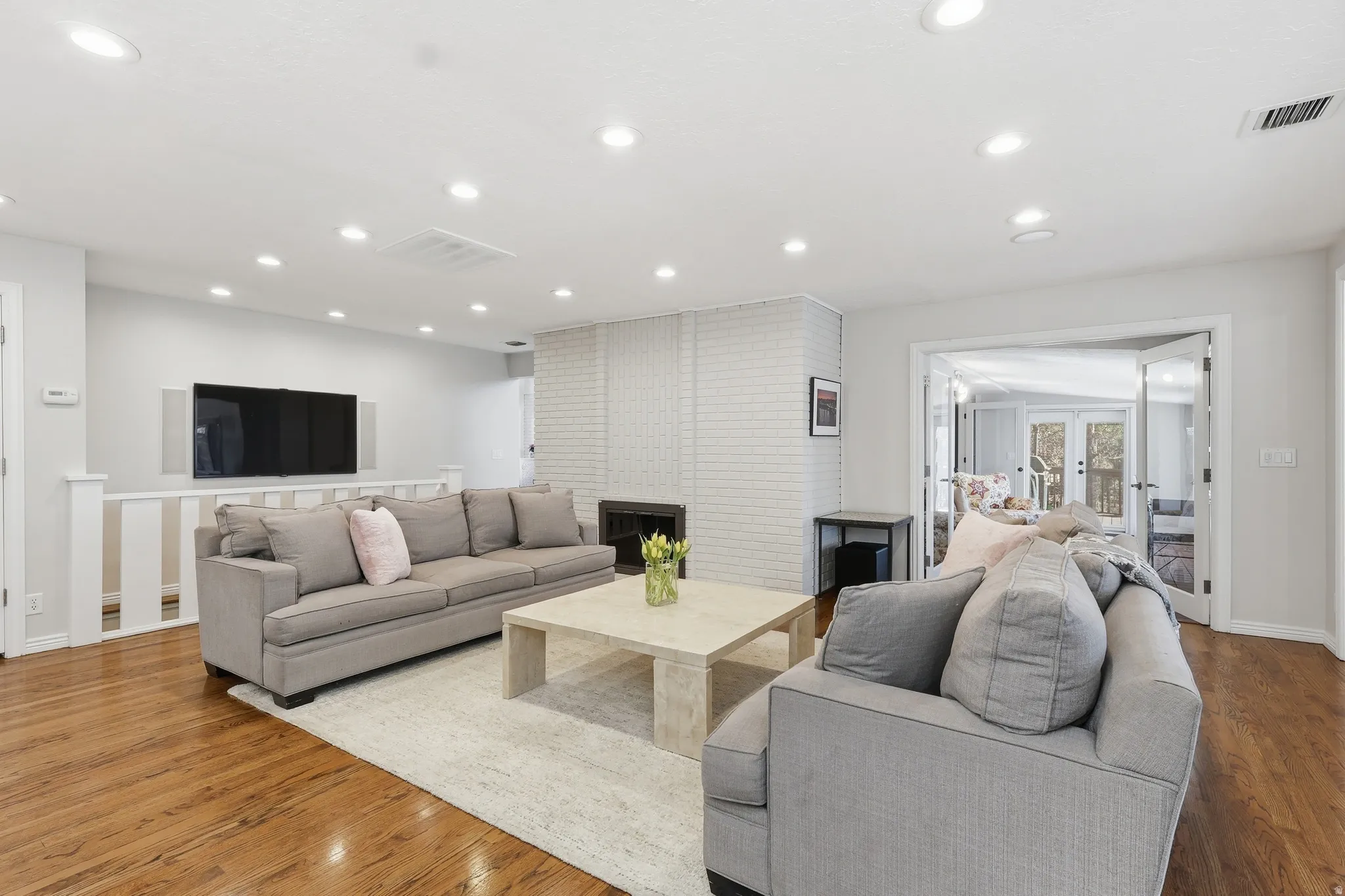 Living area with wood finished floors, french doors, recessed lighting, and a fireplace