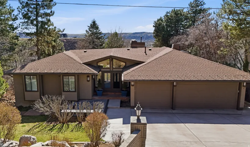 View of front facade with roof with shingles, a garage, concrete driveway, and a chimney