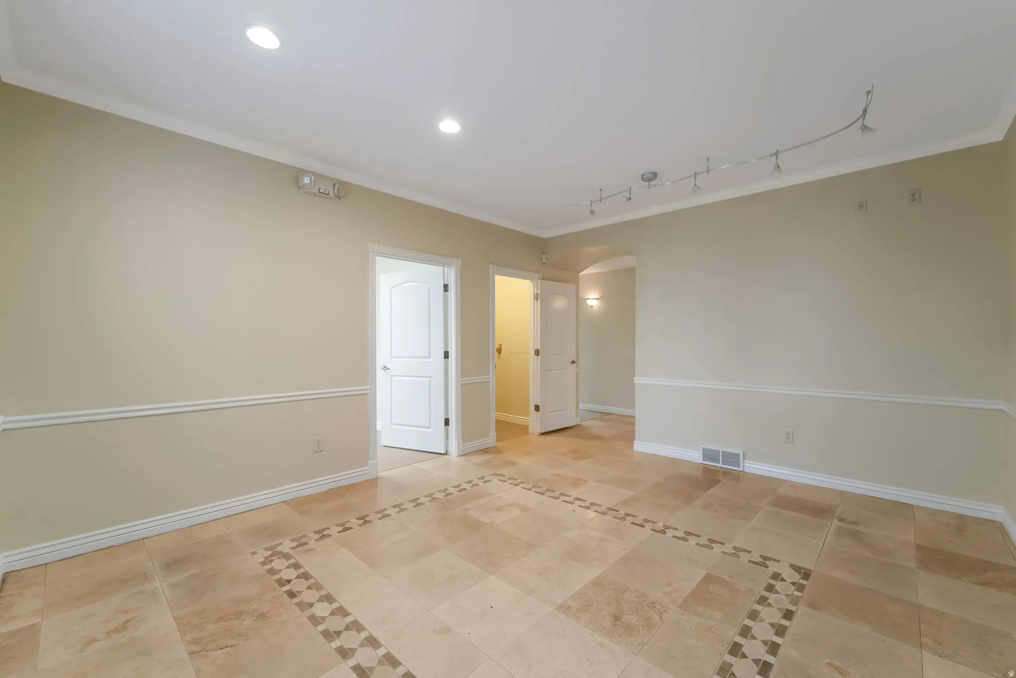 Spare room with arched walkways, crown molding, recessed lighting, and light tile patterned flooring