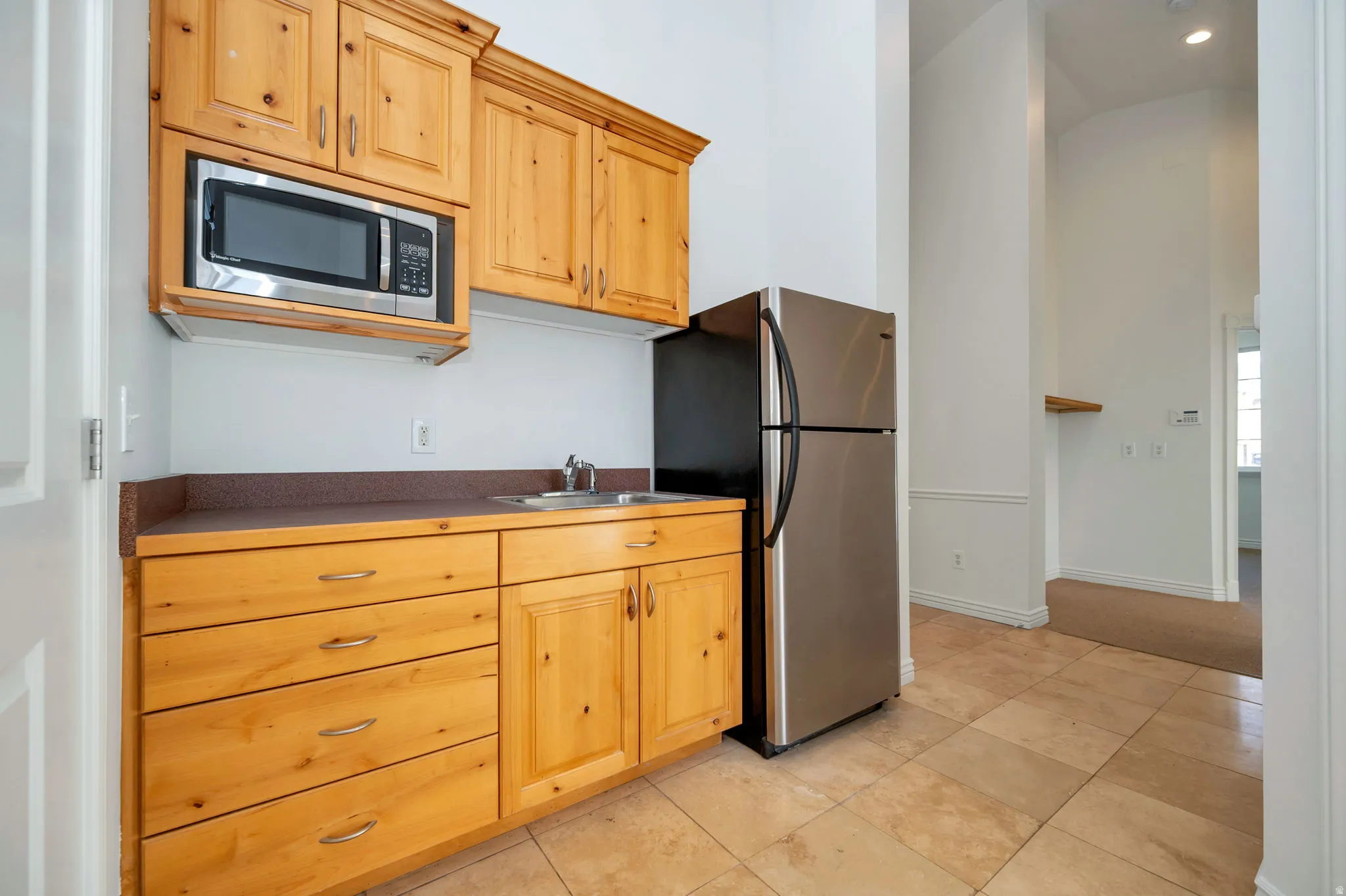 Kitchen featuring stainless steel appliances, dark countertops, recessed lighting, a high ceiling, and light wood finish cabinets