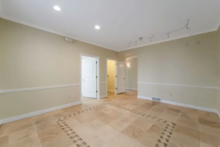 Spare room with arched walkways, crown molding, recessed lighting, and light tile patterned flooring