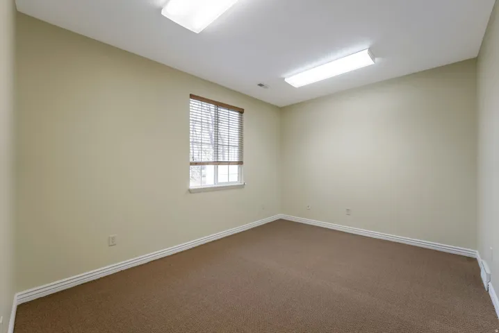 Spare room with dark carpet and baseboards