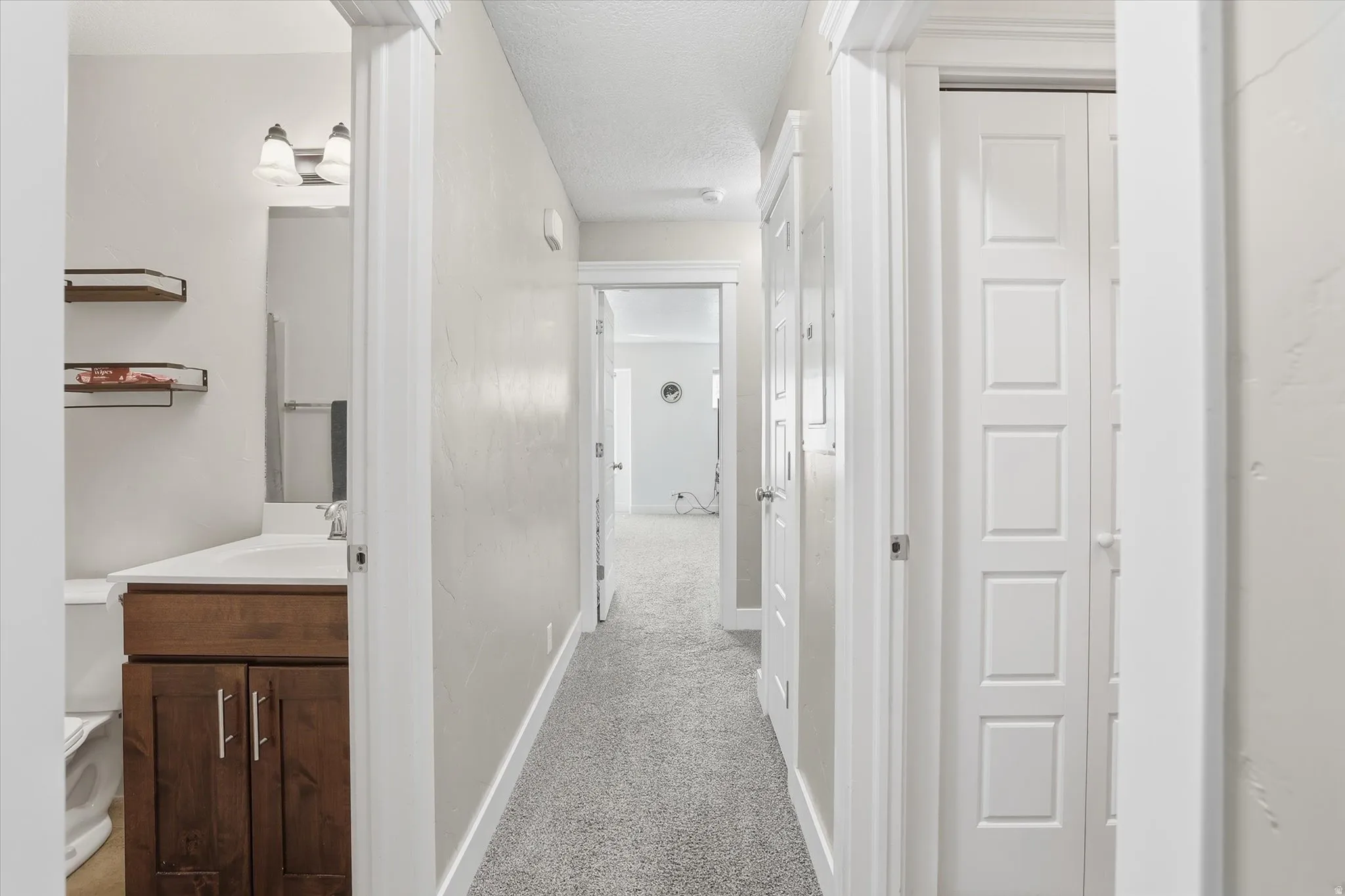 Hall featuring light colored carpet and a textured ceiling