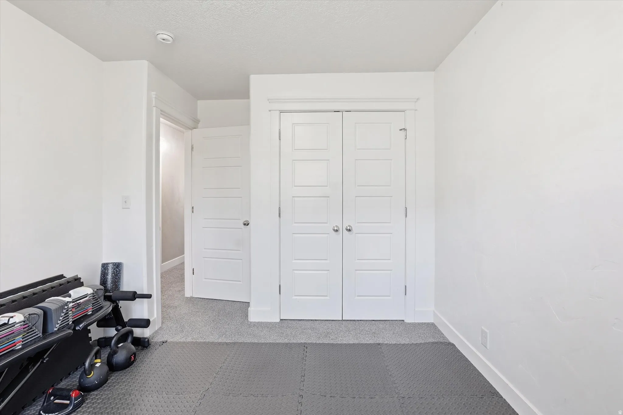 Exercise area with light colored carpet and baseboards