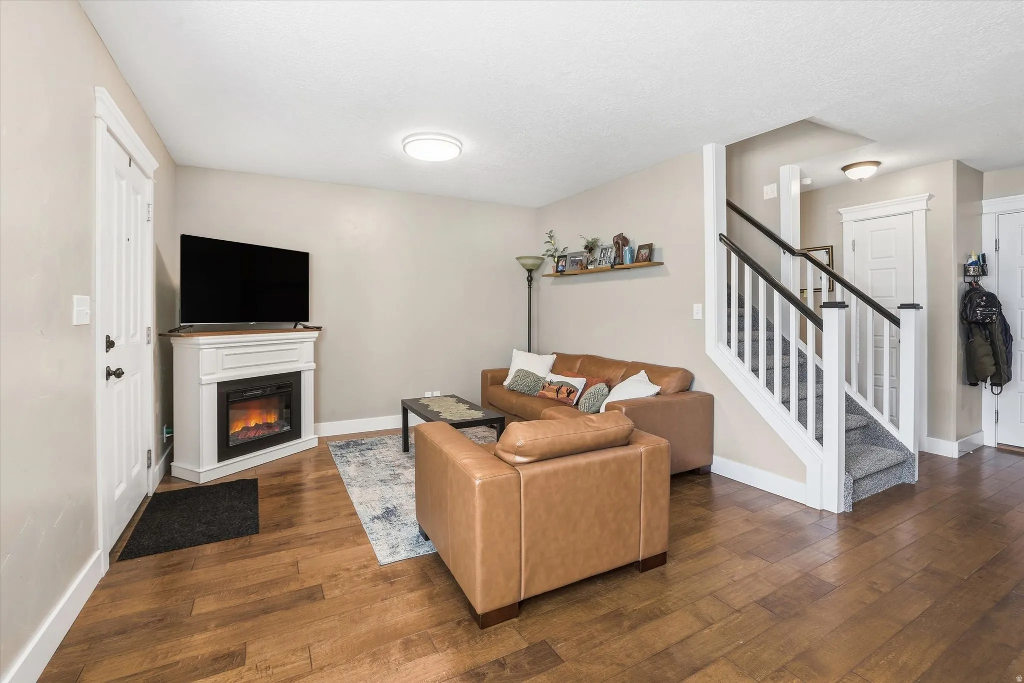 Living room featuring dark wood-type flooring and a glass covered fireplace