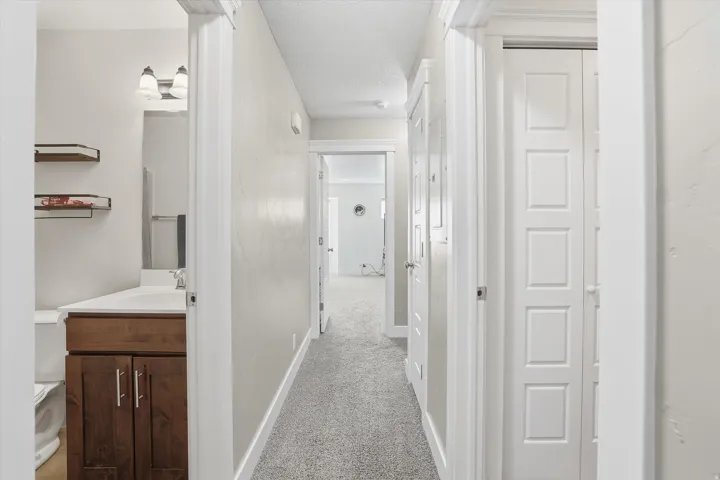 Hall featuring light colored carpet and a textured ceiling
