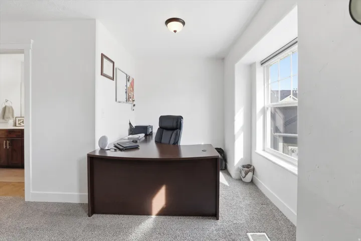 Office area featuring light carpet and baseboards