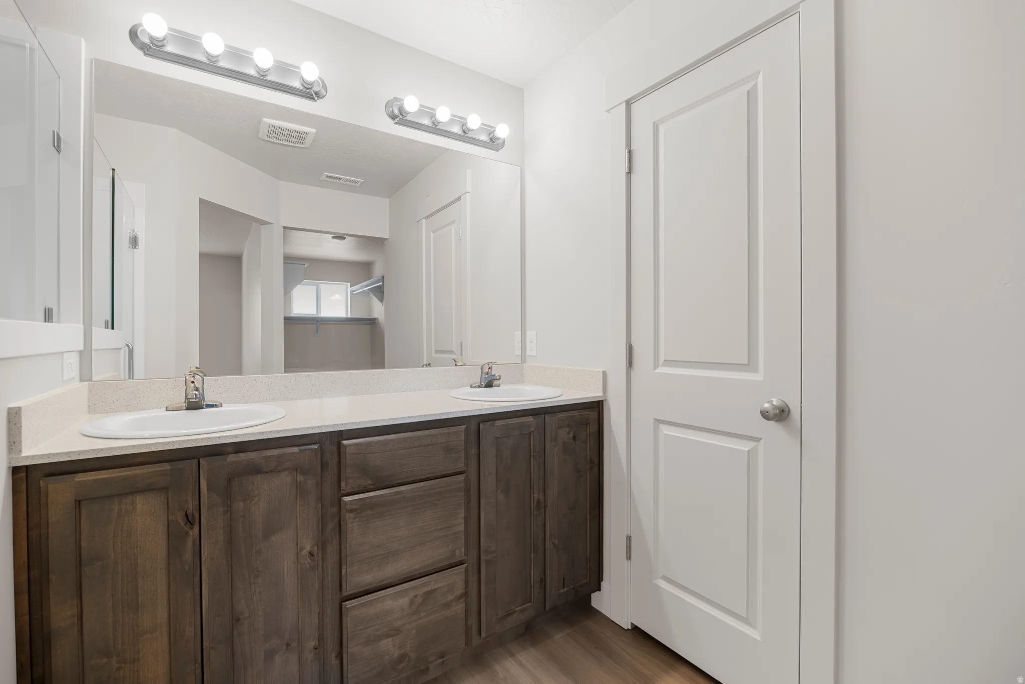 Full bathroom featuring double vanity and dark wood-type flooring