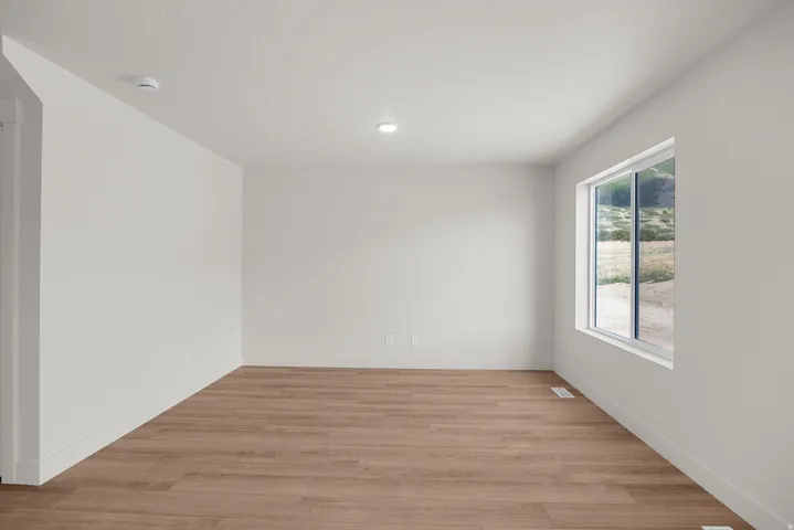 Empty room featuring light wood finished floors and a textured ceiling