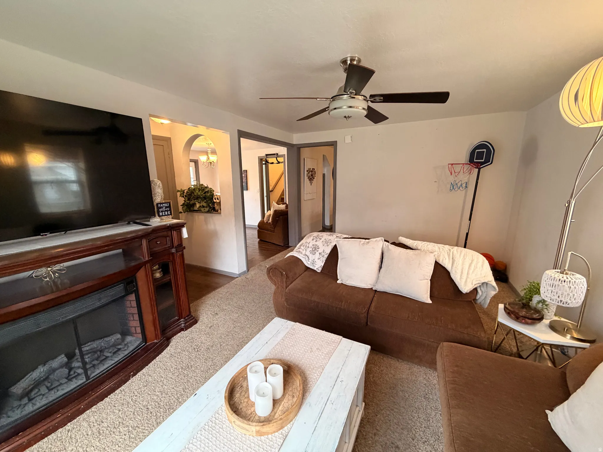 Living area featuring arched walkways, a ceiling fan, and a fireplace