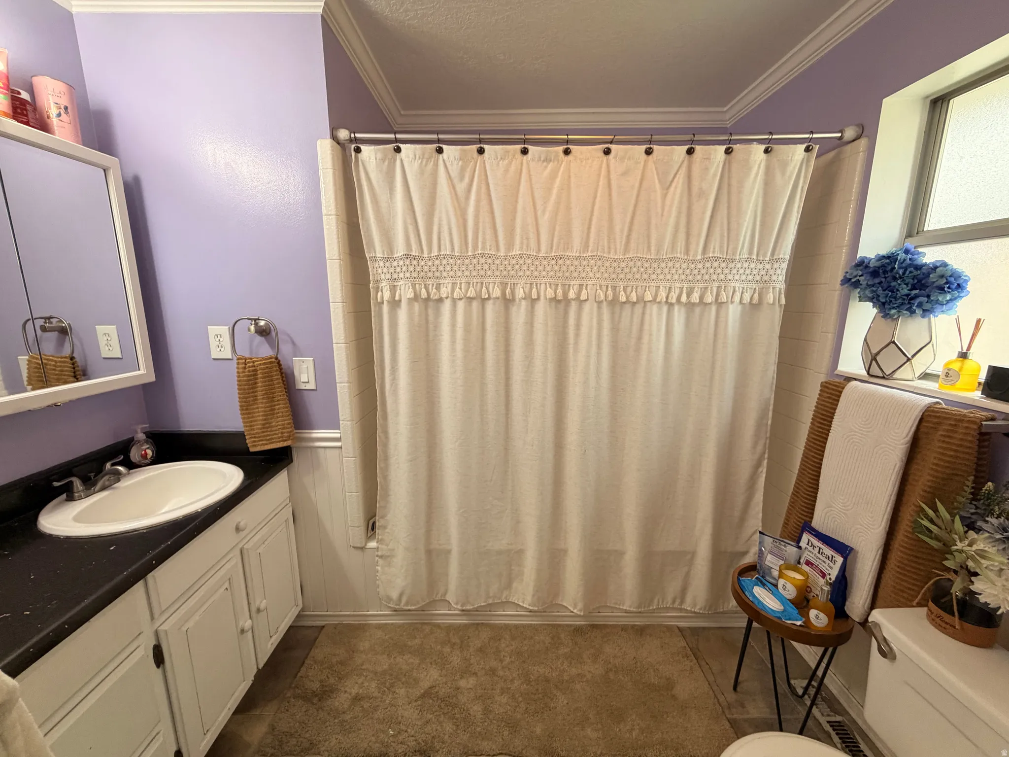 Full bathroom featuring ornamental molding, vanity, shower / bath combo with shower curtain, and a textured ceiling