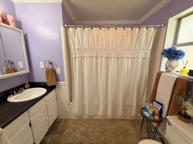 Full bathroom featuring ornamental molding, vanity, shower / bath combo with shower curtain, and a textured ceiling