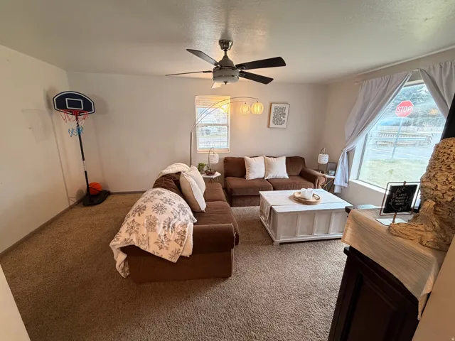 Living area featuring ceiling fan, carpet flooring, and a textured ceiling