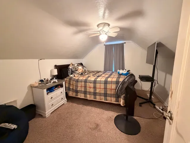 Bedroom with lofted ceiling, carpet flooring, and ceiling fan