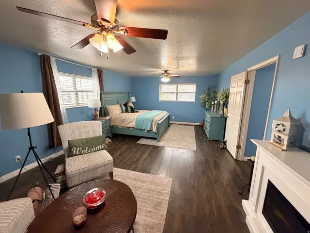 Bedroom with dark wood-style flooring, a textured ceiling, and a ceiling fan