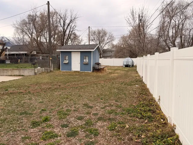 Fenced backyard featuring a storage shed