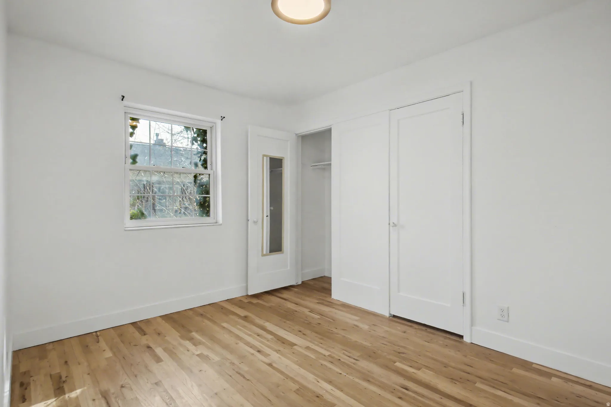 Unfurnished bedroom featuring light wood-style flooring and a closet