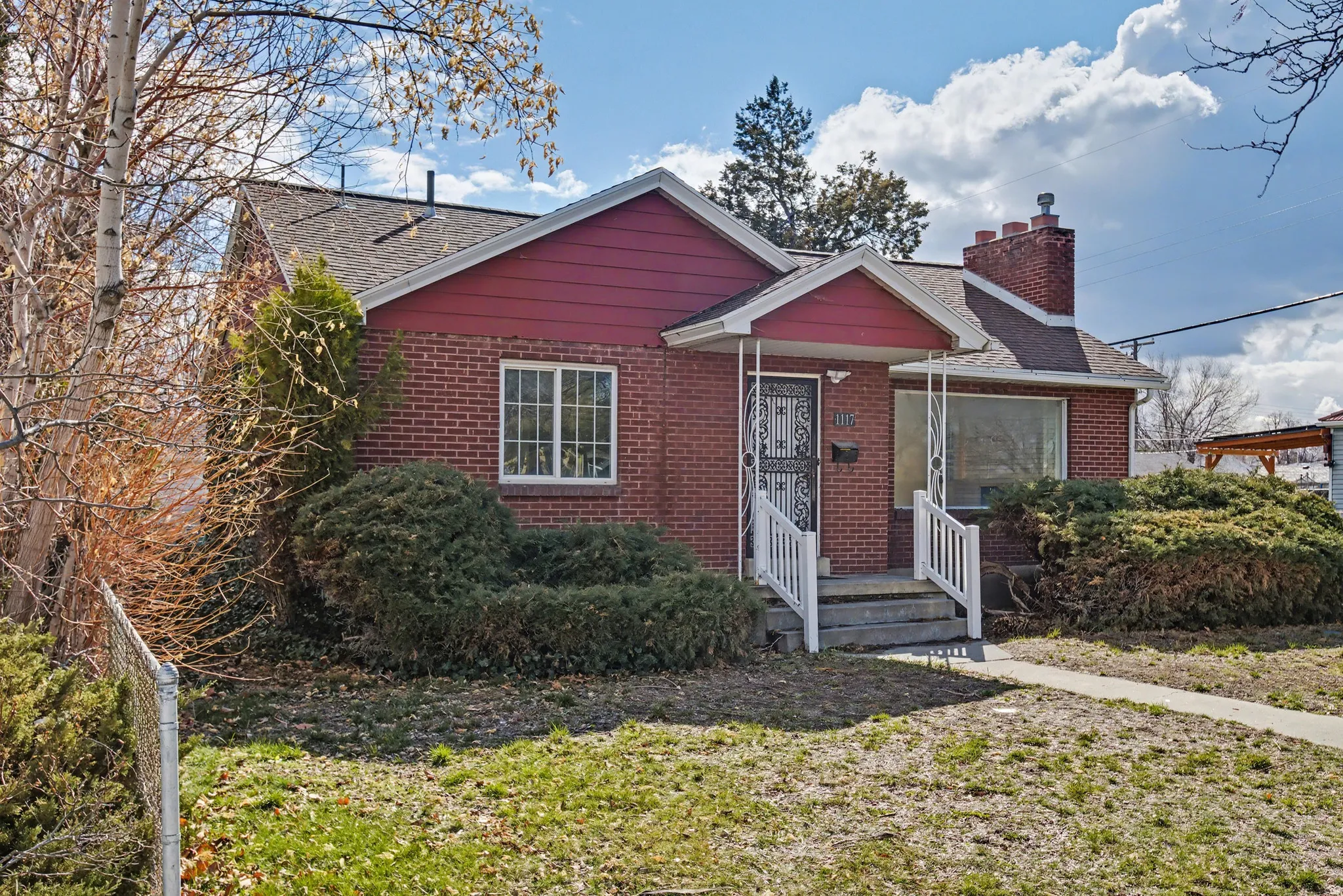 View of front of property with brick siding, roof with shingles, a chimney, and a front yard