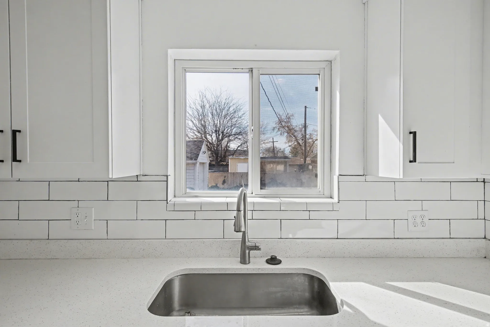 Kitchen view of light stone counters, white cabinets, and tasteful backsplash