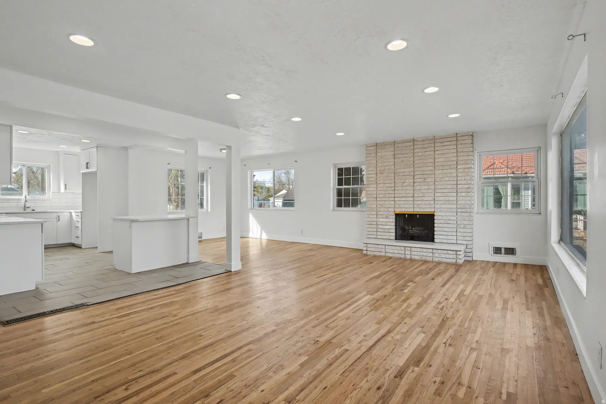 Unfurnished living room featuring light wood-style floors, a fireplace, plenty of natural light, and recessed lighting