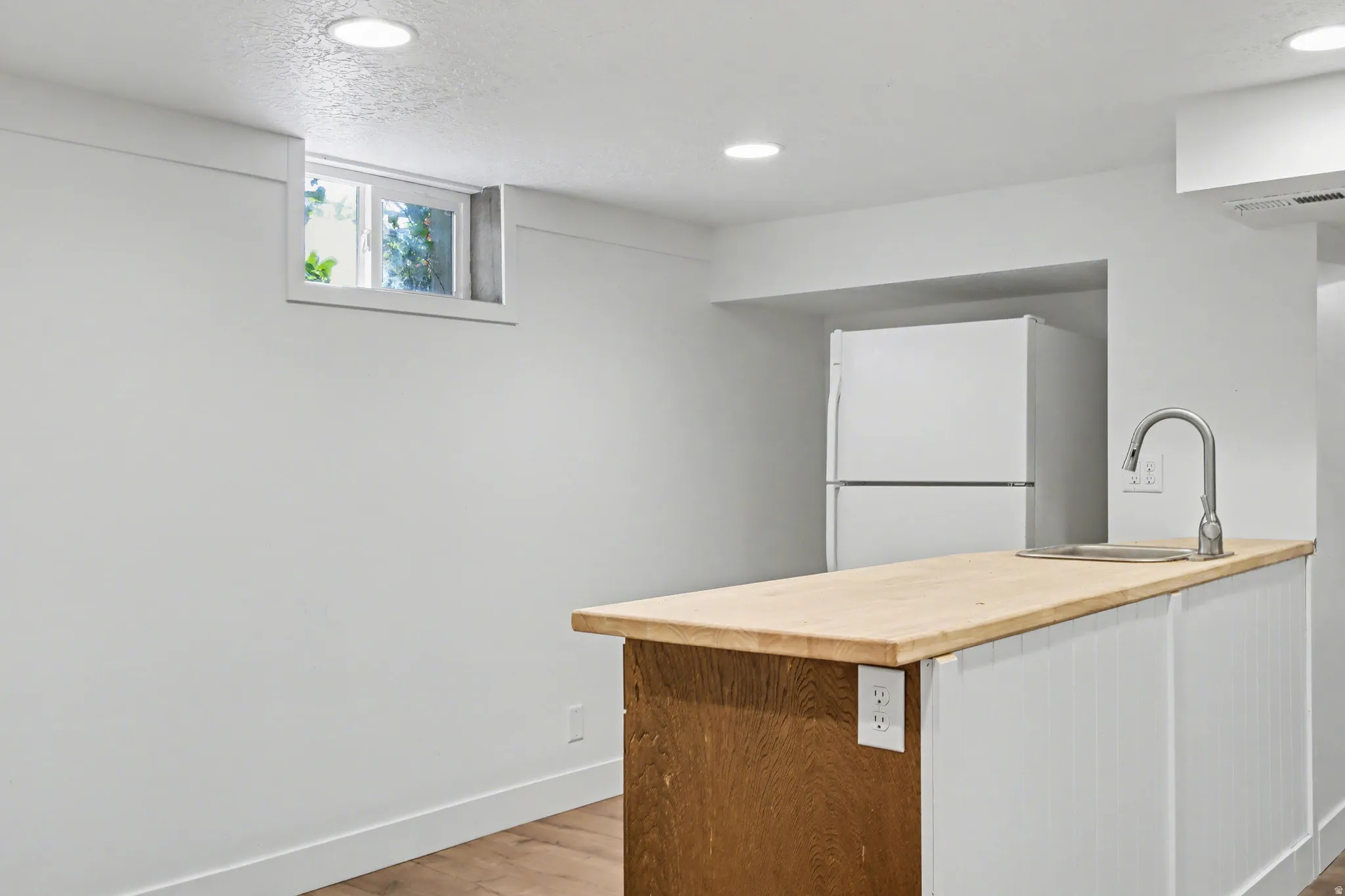 Kitchen featuring freestanding refrigerator, light wood finished floors, recessed lighting, a peninsula, and wood counters
