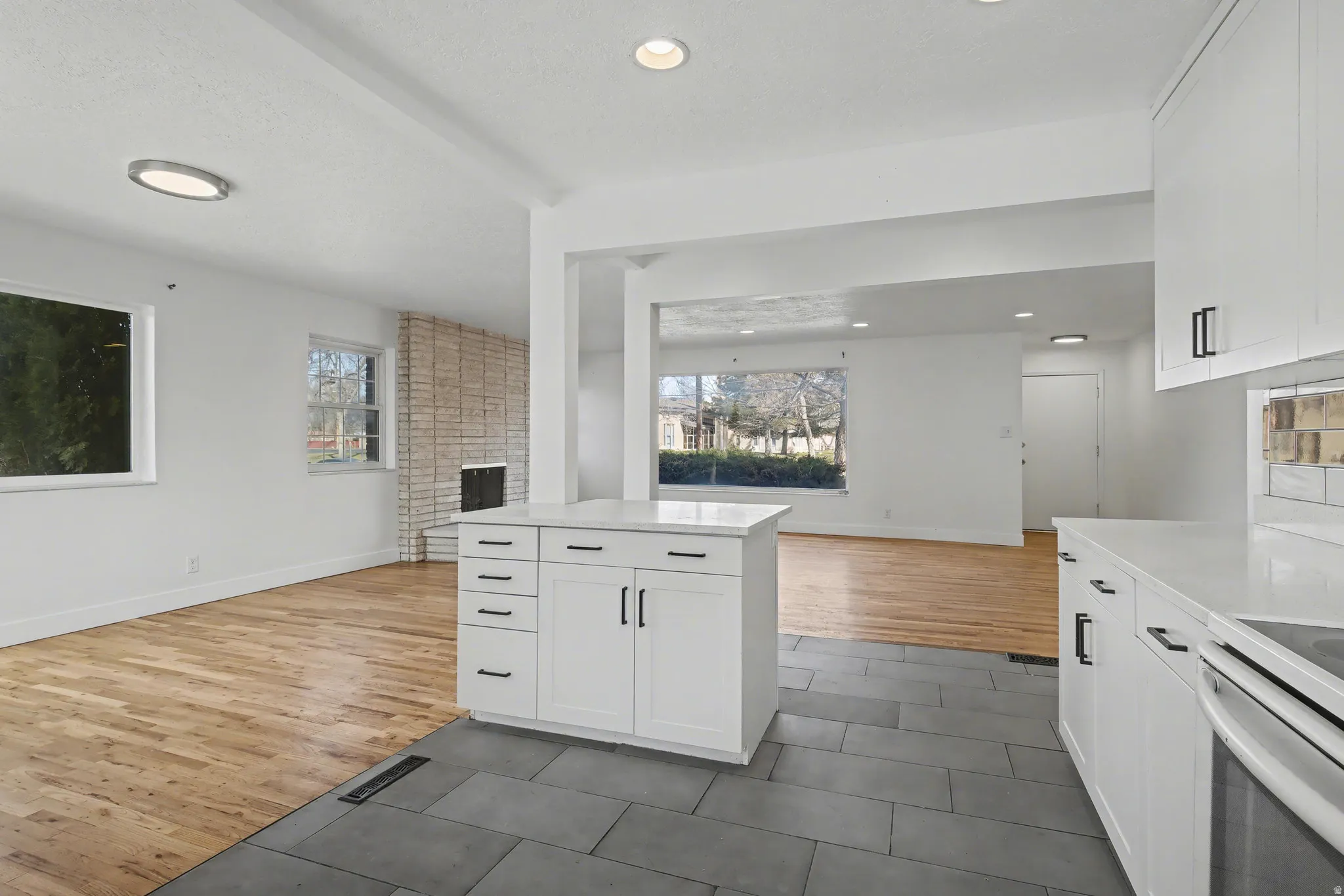 Kitchen with white cabinetry, open floor plan, light tile patterned floors, light stone countertops, and recessed lighting