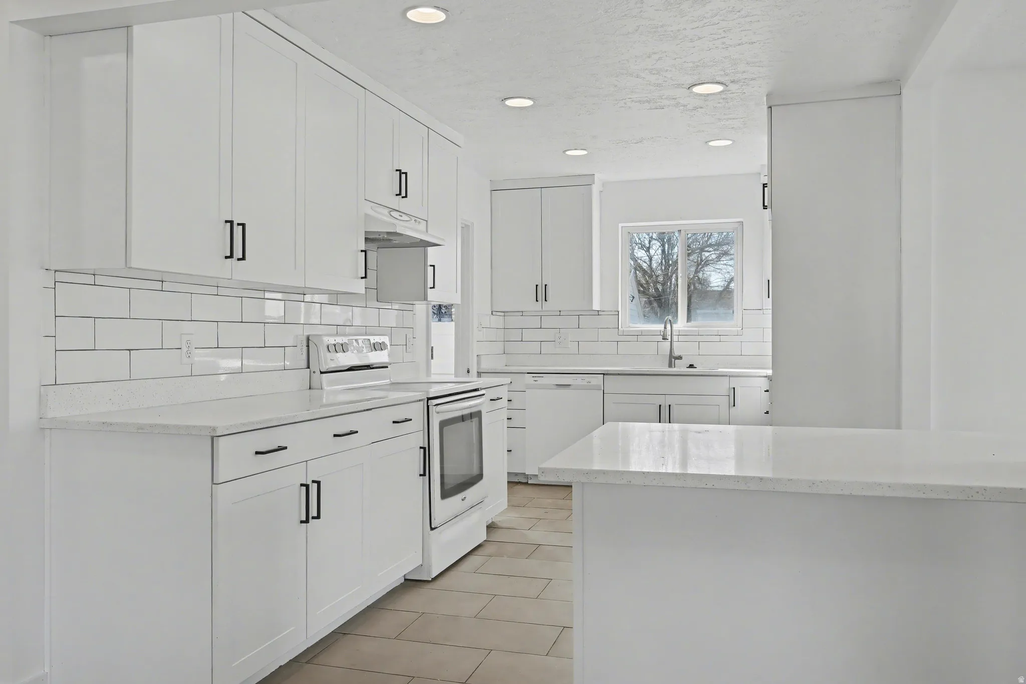 Kitchen with white cabinets, white appliances, tasteful backsplash, light stone countertops, and recessed lighting