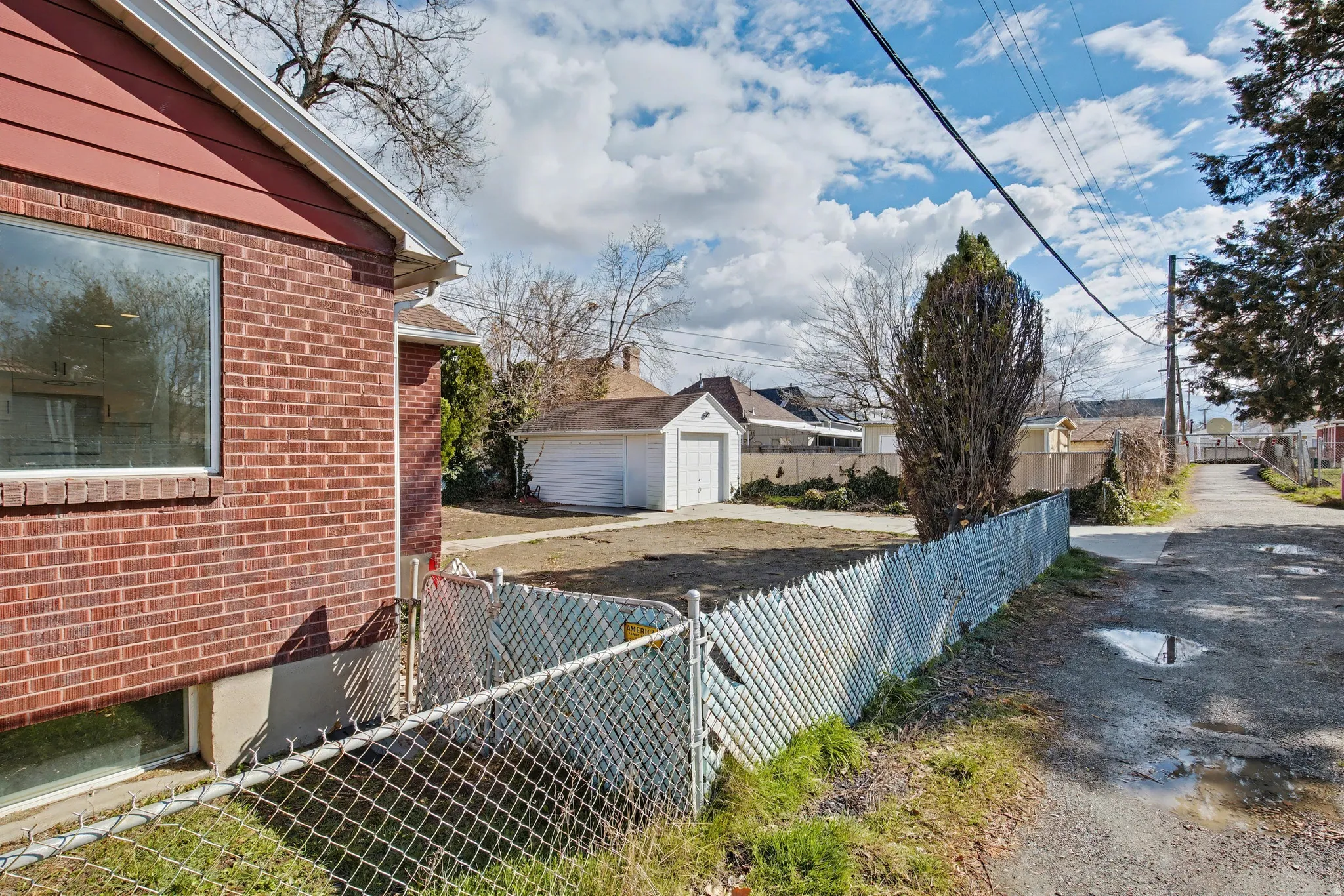 View of side of home with a detached garage, brick siding, an outdoor structure, and a residential view