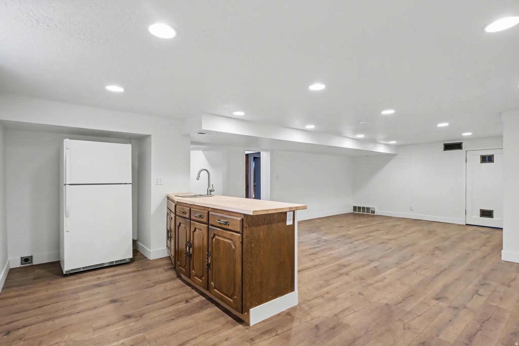 Kitchen featuring freestanding refrigerator, open floor plan, light wood-type flooring, wood counters, and recessed lighting