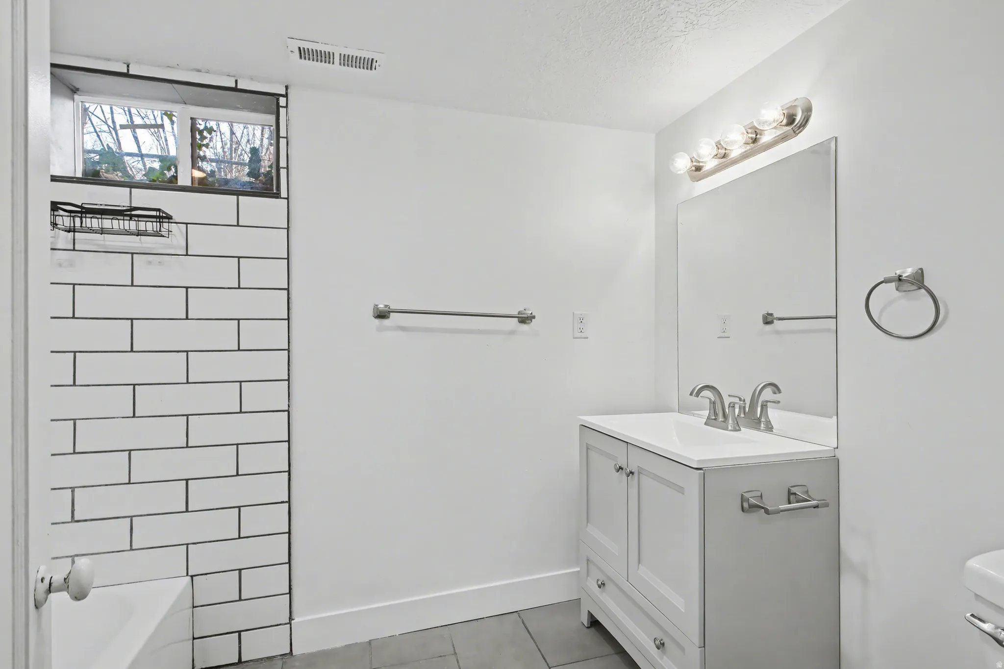 Bathroom with vanity, light tile patterned floors, shower / bathtub combination, and a textured ceiling