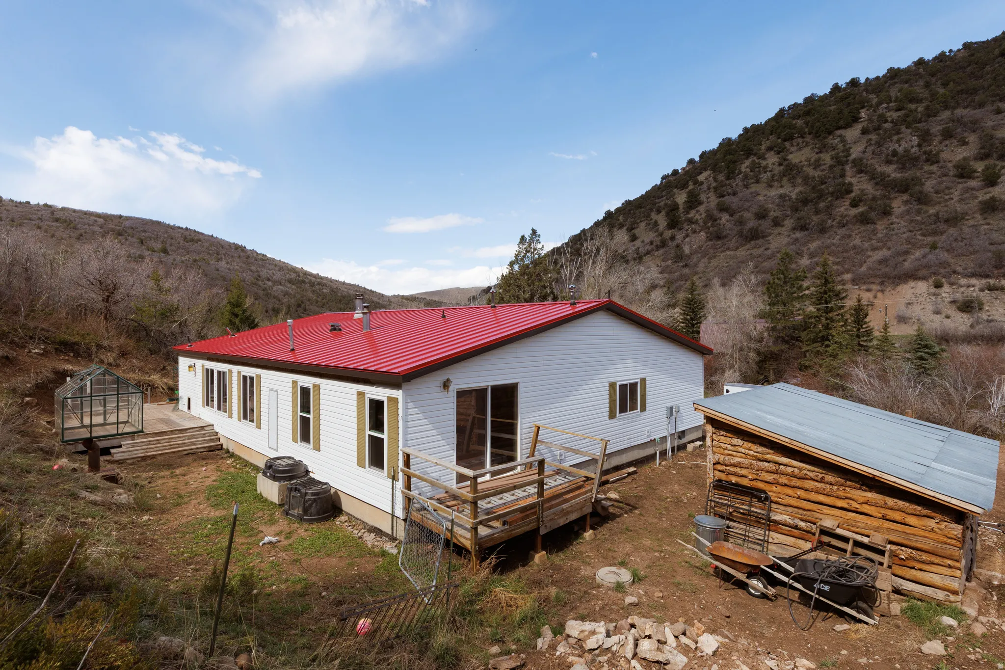 View of house with a metal roof, accessory building, greenhouse and a deck with mountain view