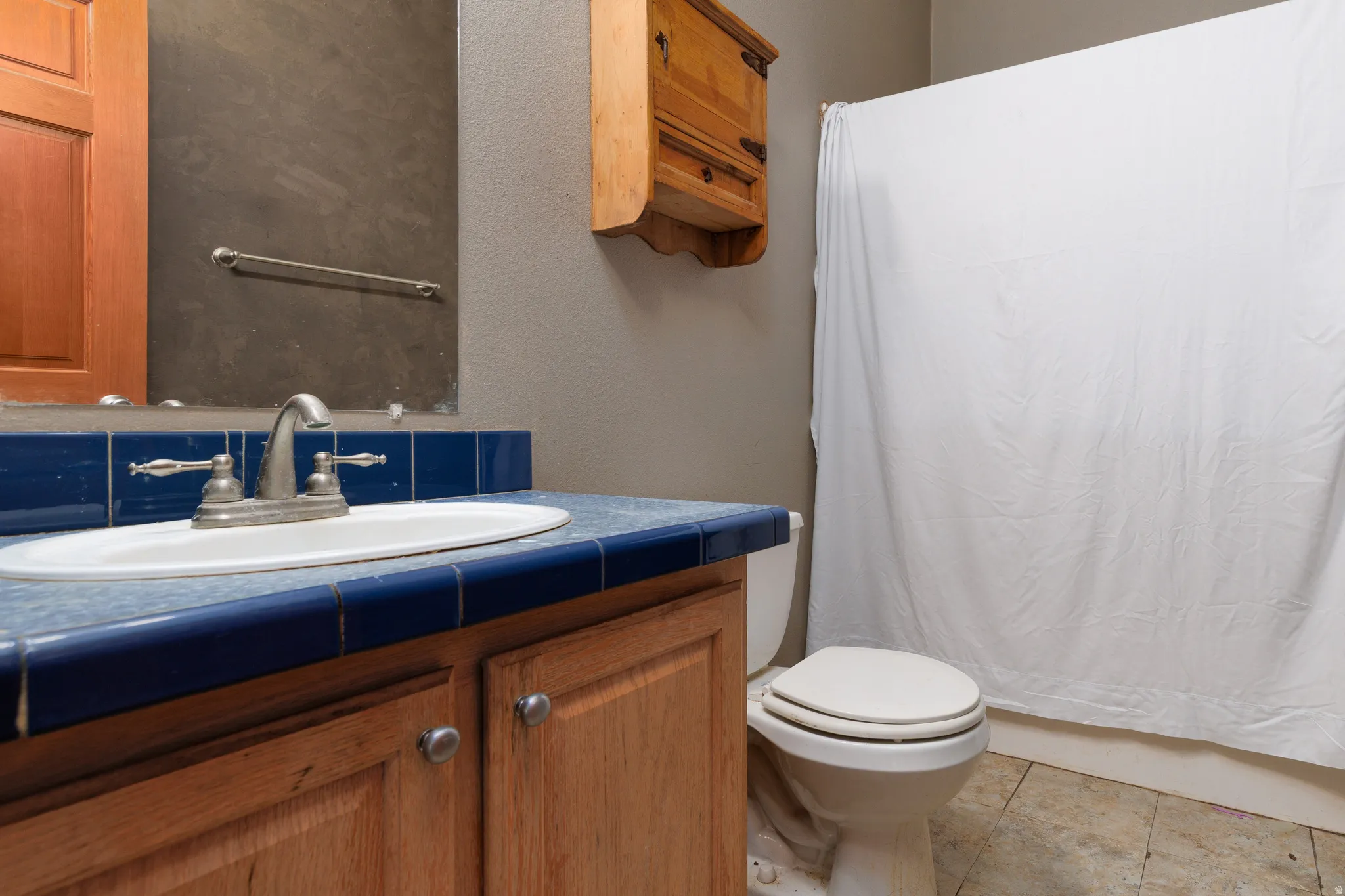 Full bath featuring vanity, a textured wall, and light tile patterned flooring