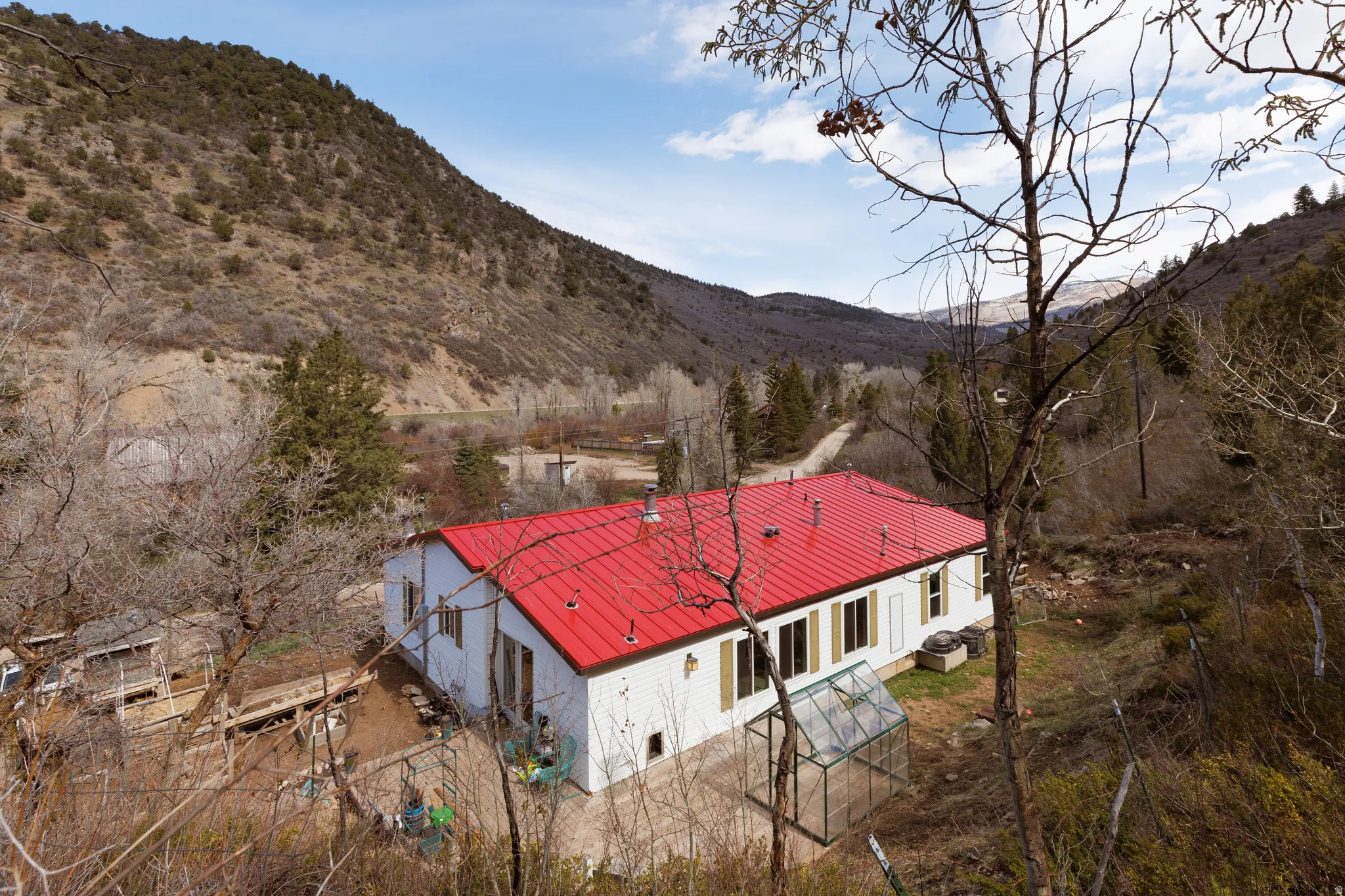 View of house with a metal roof, accessory building, greenhouse and a deck with mountain view