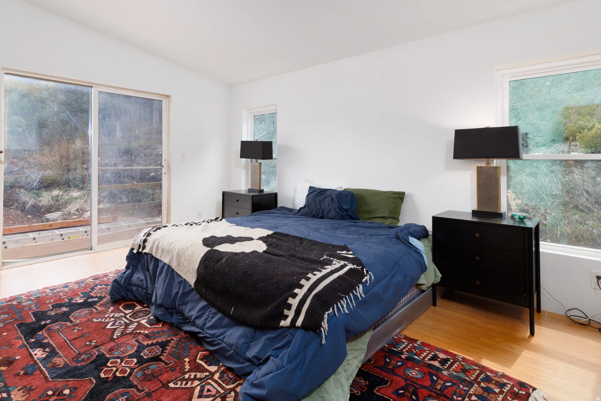 Bedroom featuring  light wood-style floors, access to outside, vaulted ceiling, and multiple windows