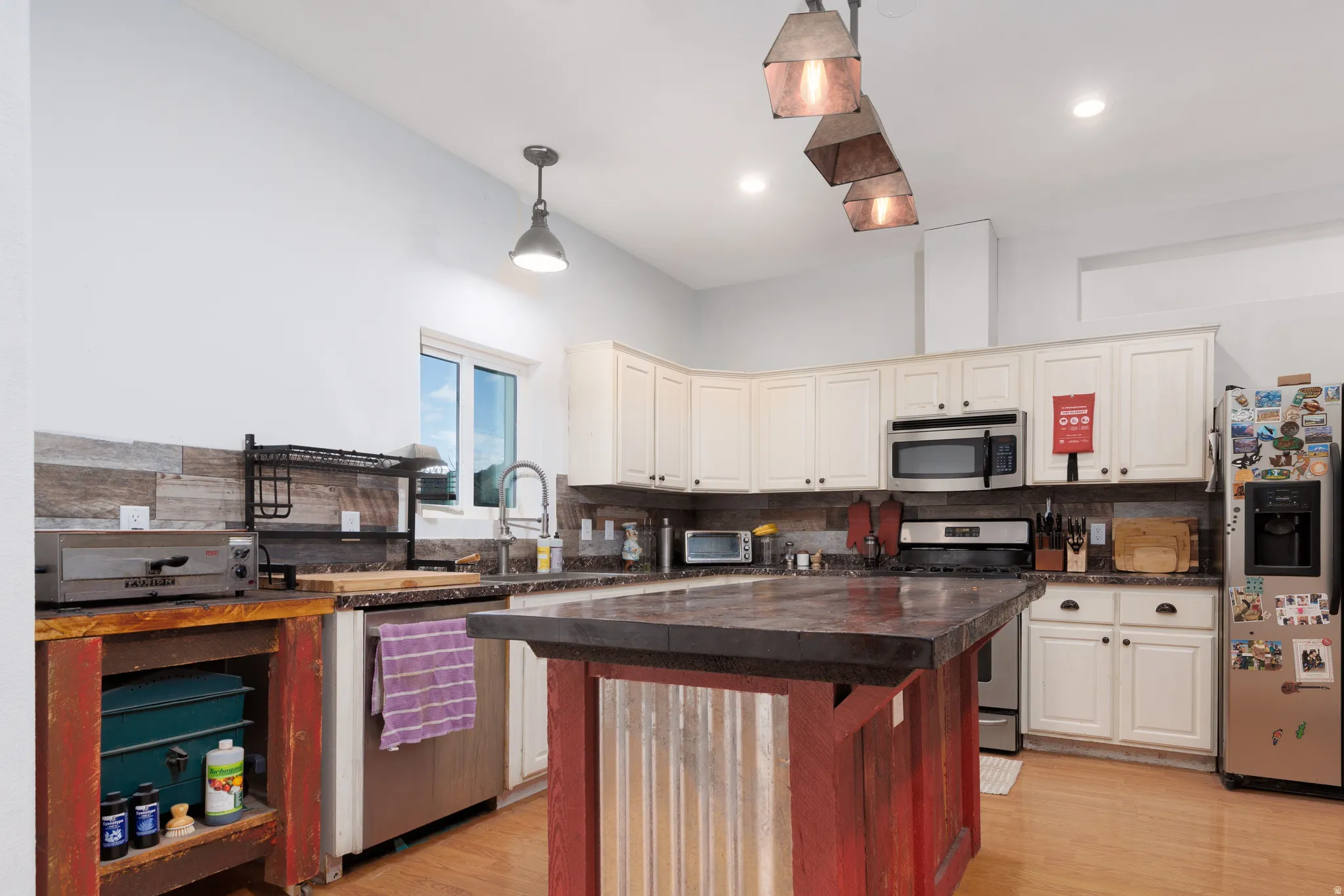 Kitchen featuring stainless steel appliances, a center island, light wood-type flooring, backsplash, and two tone color scheme