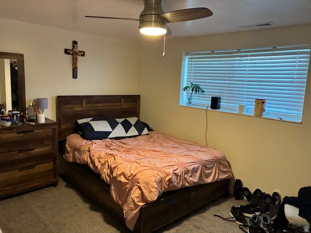 Carpeted bedroom with a ceiling fan