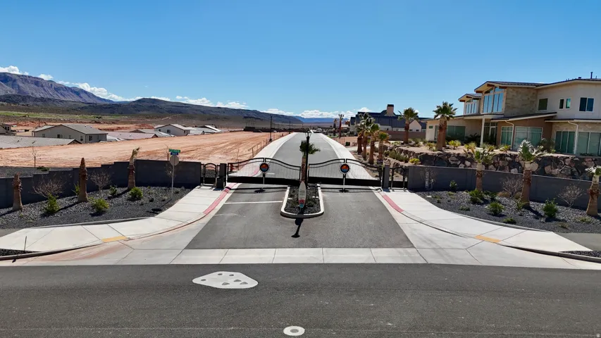 View of asphalt road with sidewalks, a gated entry, a gate, a residential view, and a mountain view