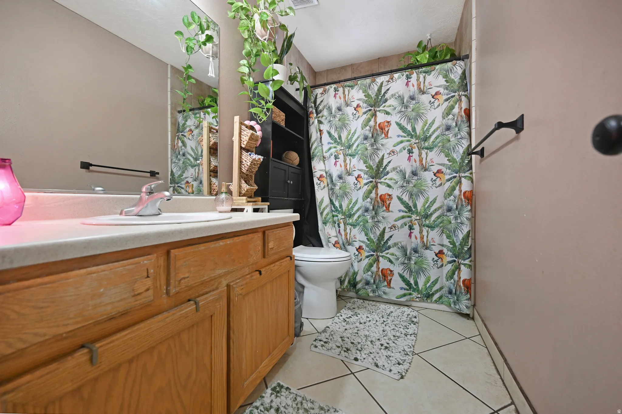 Bathroom featuring a shower with shower curtain, vanity, and light tile patterned floors